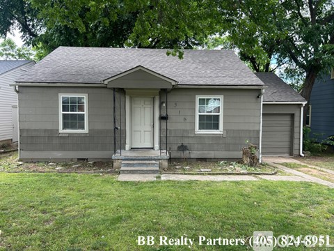 A house with a white door and two windows is for sale.