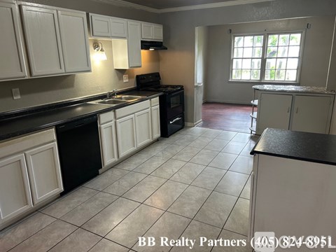 A kitchen with white cabinets and black appliances.