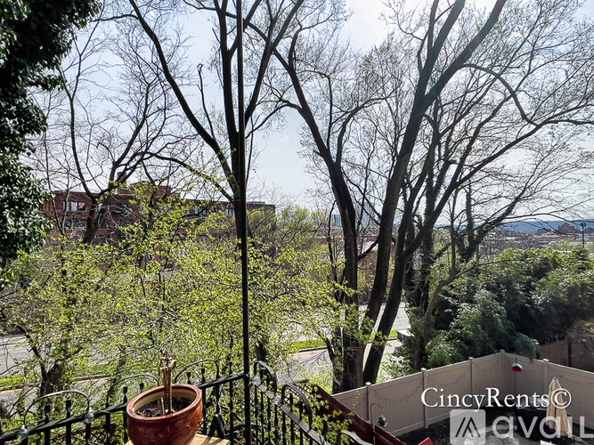 A balcony view of a tree-lined street with a building in the distance.