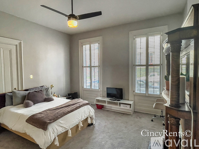 A bedroom with a bed, a television, and a window.