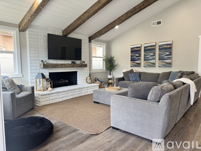 A living room with a fireplace and a grey couch.