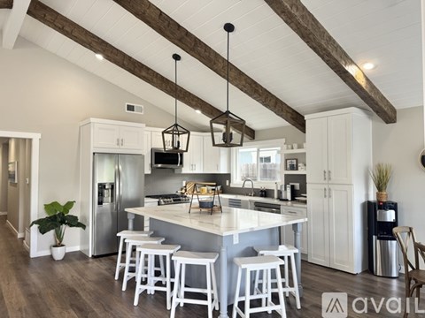 A kitchen with white cabinets and a large island with four stools.