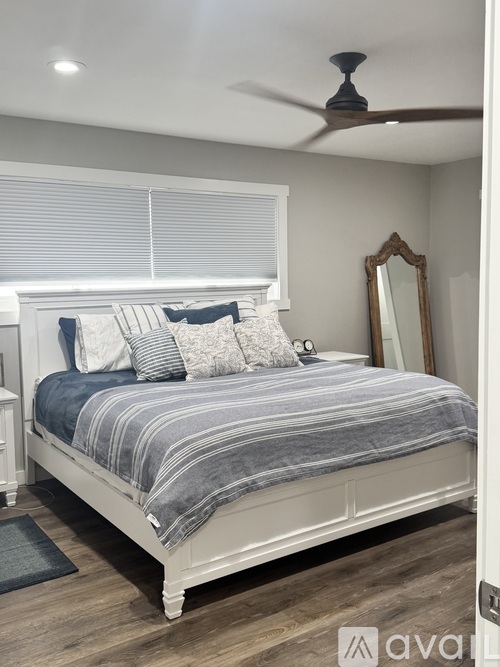 A bedroom with a bed, a mirror, and a ceiling fan.