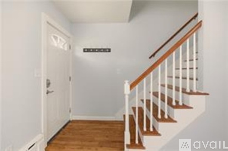 A hallway with a wooden staircase and a white door.
