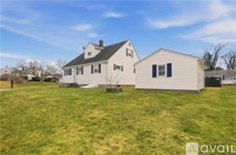 A white house with a black roof is situated in a grassy area.