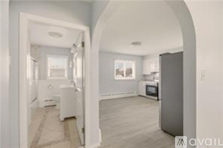 A modern kitchen with a refrigerator and a dining area with a table and chairs.