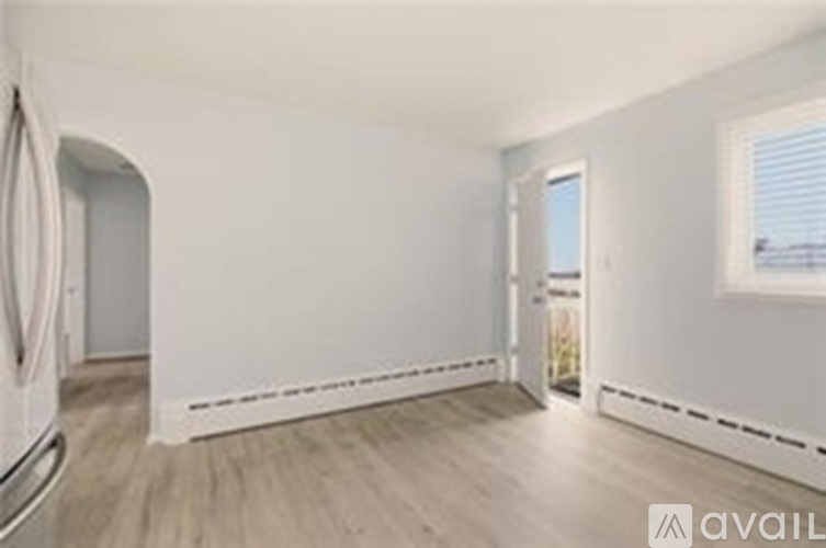 A spacious room with wooden flooring and white walls.