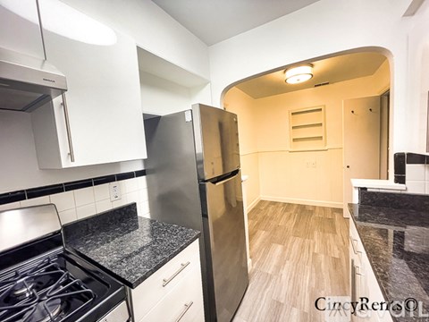 A kitchen with a stove, refrigerator, and cabinets.