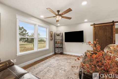 A living room with a brown leather couch and a ceiling fan.