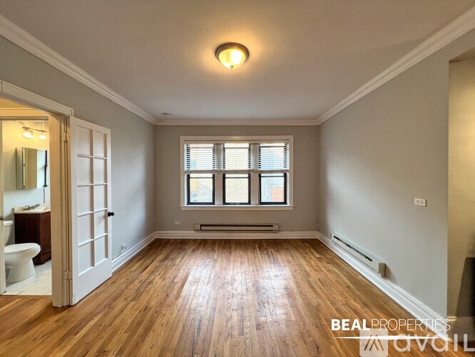 A spacious room with wooden floors and a large window.