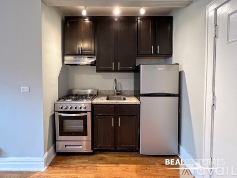 A kitchen with dark brown cabinets and a stainless steel refrigerator.