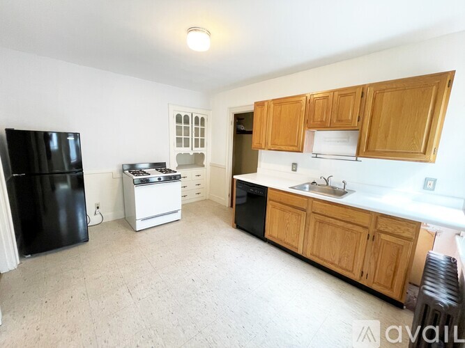 A kitchen with wooden cabinets and a black fridge.