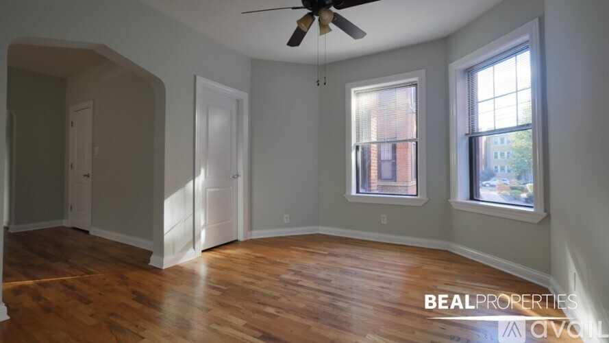 A room with a ceiling fan and two windows.