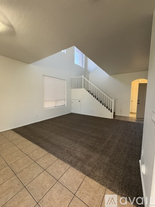 A spacious room with a staircase in the background.