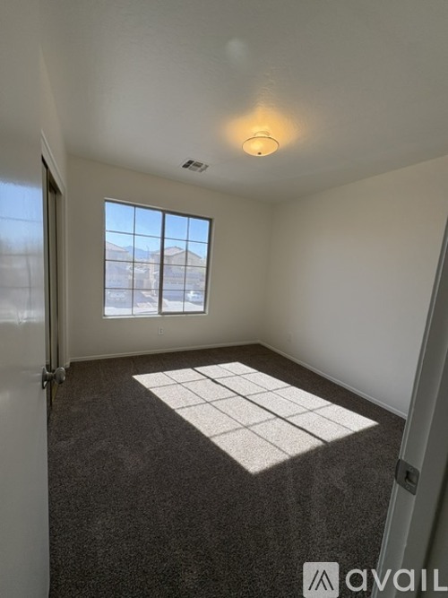A room with a carpeted floor and a window overlooking a building.