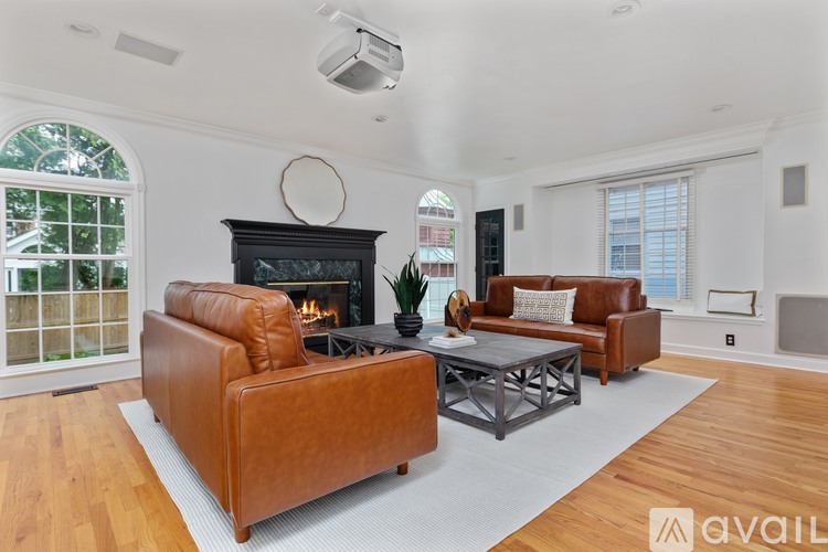 A kitchen with black cabinets and a large island with a circular patterned rug in front.