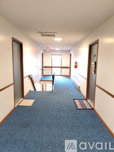 A hallway with a blue carpet and wooden walls.