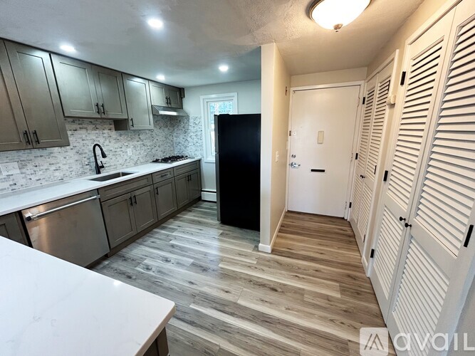 A kitchen with a black refrigerator and wooden floors.