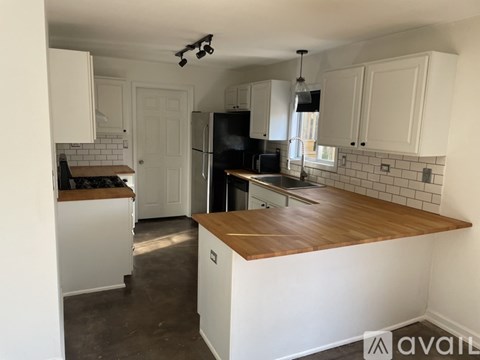 A kitchen with white cabinets and a wooden countertop.