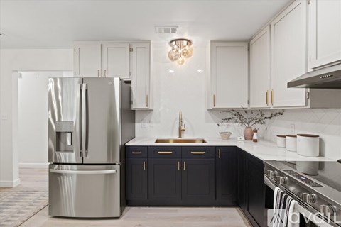 A modern kitchen with a stainless steel refrigerator and black cabinets.