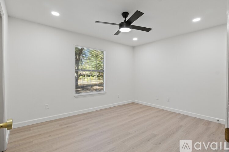 A spacious room with a ceiling fan and a picture of a tree-lined street on the wall.