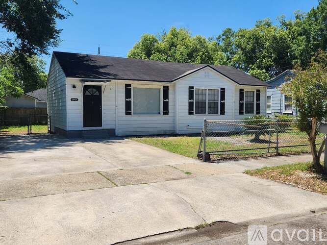 A small white house with a black door and windows is for sale.