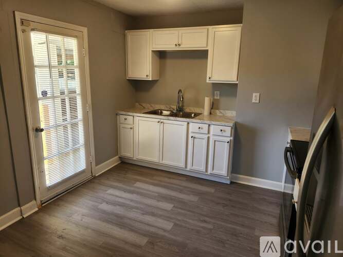 A kitchen with white cabinets and a wooden floor.