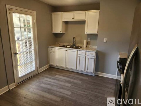 A kitchen with white cabinets and a wooden floor.