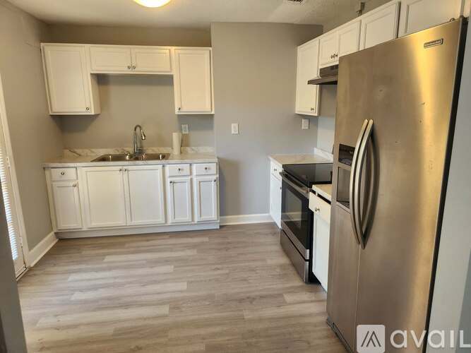 A kitchen with white cabinets and a stainless steel refrigerator.