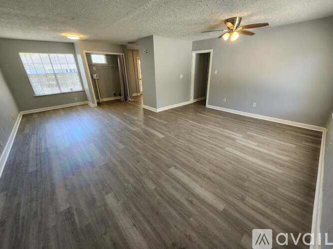 A spacious room with wood flooring and a ceiling fan.