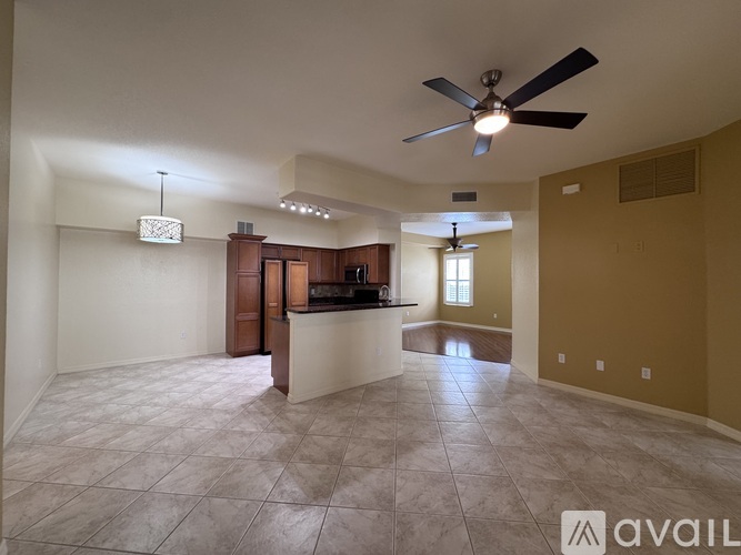 A spacious living room with a kitchen area in the background.
