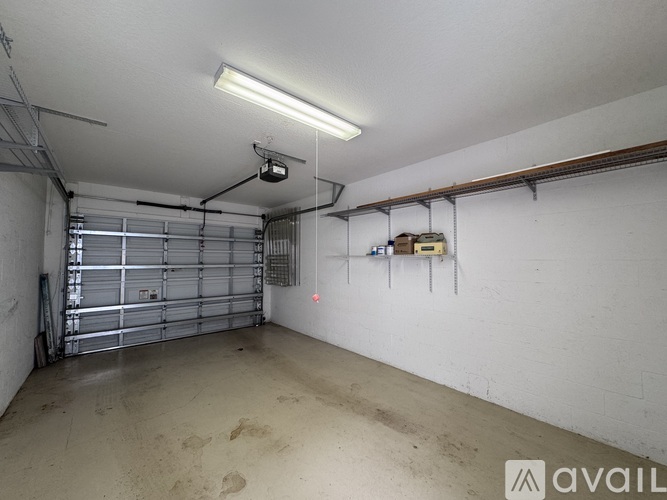 A spacious garage with a closed metal door and a white wall.