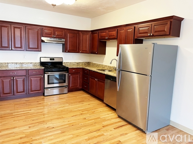 A kitchen with wooden cabinets and a stainless steel refrigerator.