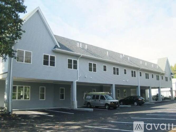 A white building with a sign that says "available" in the parking lot.