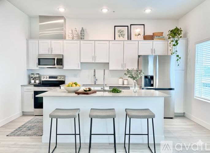 A kitchen with white cabinets and a white island with two stools.
