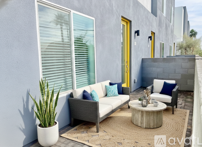 A modern outdoor living space with a grey couch, a wooden coffee table, and a potted plant.