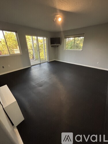 A spacious room with black flooring and a television mounted on the wall.