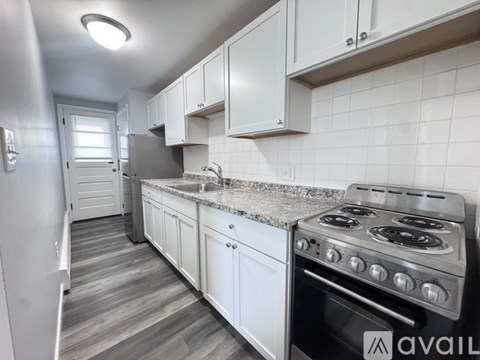 A kitchen with a stove, sink, and cabinets.
