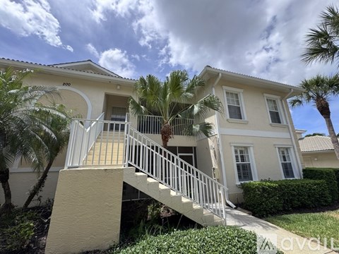 A two-story house with a balcony and stairs leading to the front door.