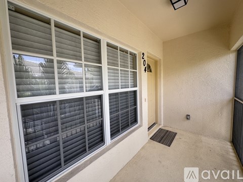A room with a window covered in blinds and a door with a number 2014 on it.