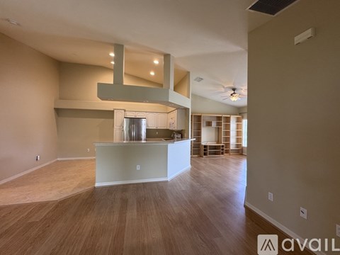 A spacious room with wooden flooring and a kitchen island in the middle.