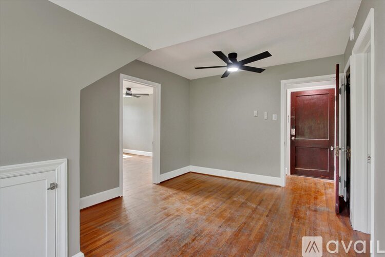 A room with a ceiling fan and wooden floors.