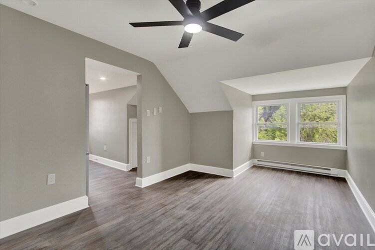 A room with a ceiling fan and a window with a view of trees.