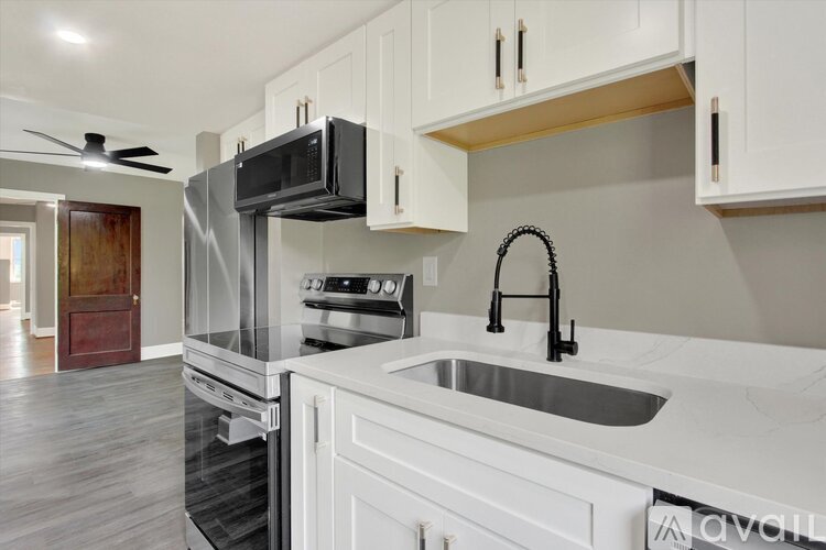 A kitchen with white cabinets and a black microwave.