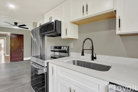 A kitchen with white cabinets and a black microwave.