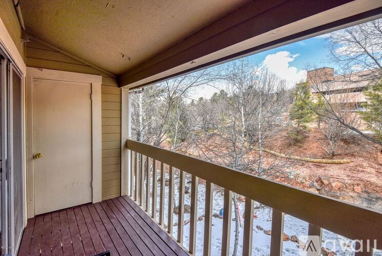A balcony with a white door and a view of a wooded area.