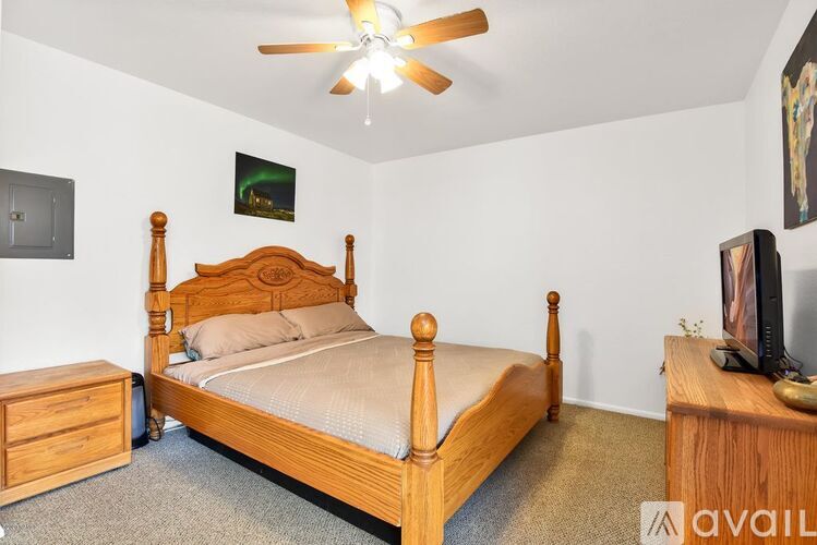 A bedroom with a bed, dresser, and ceiling fan.