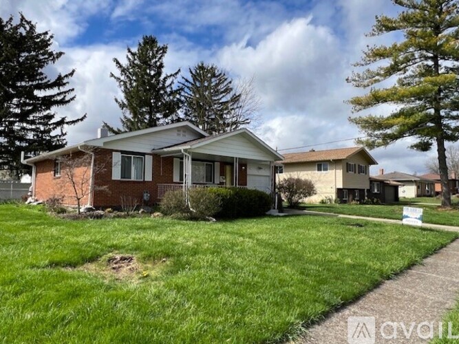A house with a white fence and a tree in front of it.