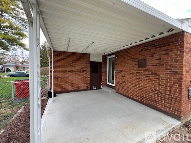 A covered porch area with a white roof and a brick wall.