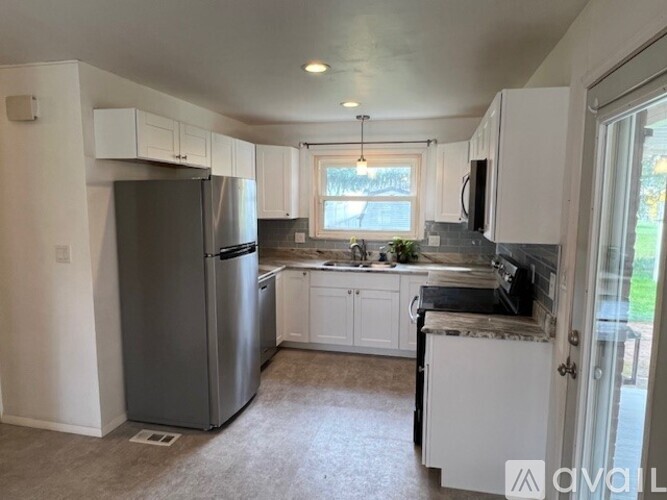 A kitchen with white cabinets and a grey fridge.